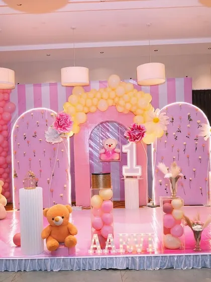 This pink floral decor for a teddy bear theme is perfectly executed. The stage features light-up arches, themed props, and a soft pink carpet, creating a dreamy and cohesive look.
