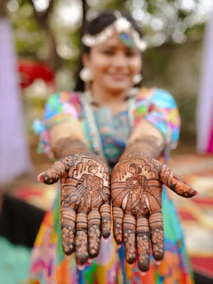 A professional shot capturing the bride-and-groom portraits on the palms, with the happy bride in the background.