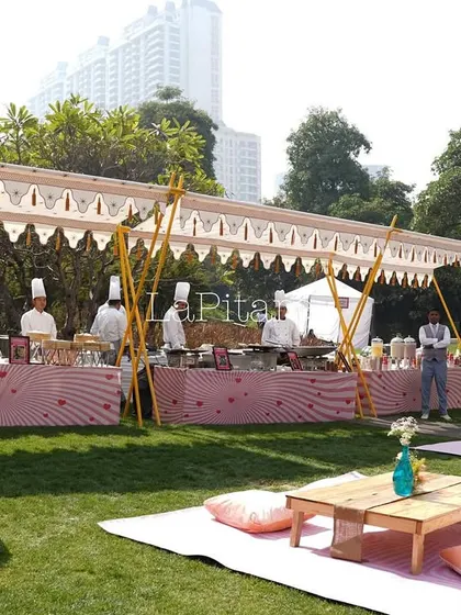 The catering station for the outdoor picnic event. We designed a long tented stall with pink and white patterned skirting to match the romantic, playful theme of the day.