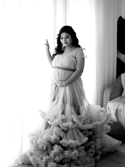 A beautiful black and white portrait by the window. The soft, natural light and the flowing gown create a timeless and ethereal feel.