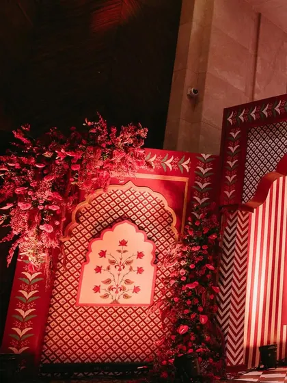 A photo booth area with a backdrop of red and white stripes and traditional Indian floral motifs, creating a culturally rich and visually striking spot.