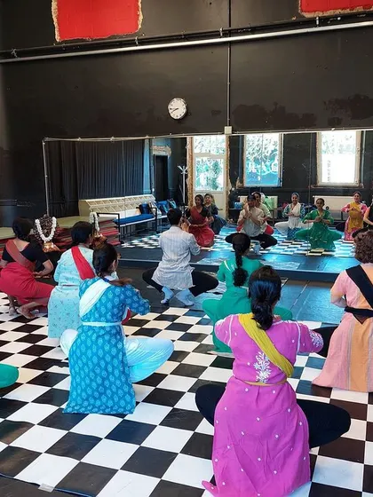 A view from the back of the class, showing students practicing a seated posture. This highlights the collective effort and shared experience of a group session.