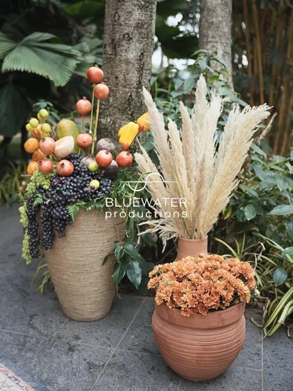 An arrangement of artificial fruits and pampas grass in rustic pots adds texture and color to the decor.