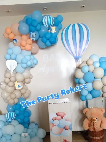 A beautiful hot air balloon themed decoration in pastel shades of blue, peach, and beige, creating a dreamy atmosphere to welcome a new baby.