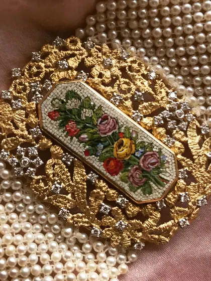 An exquisite micromosaic floral bouquet set in an ornate, lace like 18k gold frame studded with diamonds. This piece can be worn as a brooch or a pendant, a versatile heirloom that captures the charm of a vintage garden.
