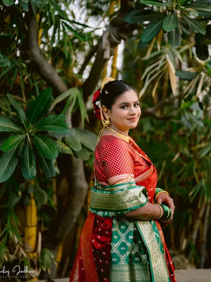 A smiling portrait of the bride, Ankita, looking radiant in her red and green wedding saree.