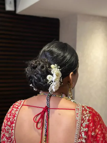 A classic bridal bun adorned with fresh white flowers. This hairstyle is perfect for a traditional Phera ceremony, offering a look of pure elegance.