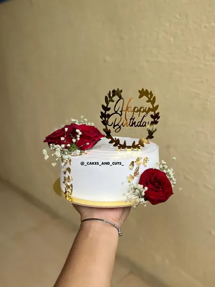 A simple and sweet cake held in hand, decorated with red roses and a gold birthday topper. Even a small cake can be a work of art.