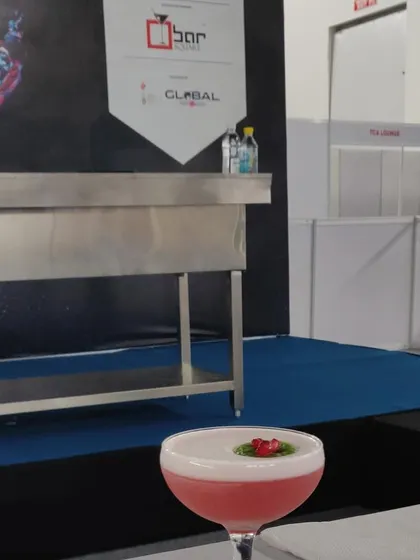 A pink, frothy cocktail with a delicate garnish, presented at a mixology competition. This showcases my experience in creating high-end, competitive level drinks that stand out.
