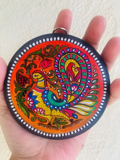 The small bird wall hanging held in hand to show its delicate size and intricate detailing. It's a perfect small gift or a charming addition to a larger gallery wall.