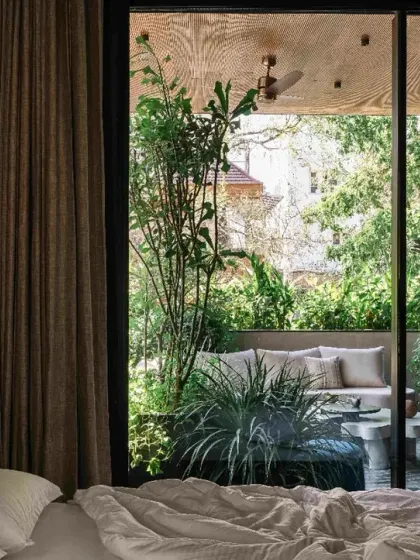 A view from a bedroom in Project 1374 looking out onto a private, plant-filled terrace. Large sliding glass doors dissolve the boundary, allowing the garden to become an extension of the living space.