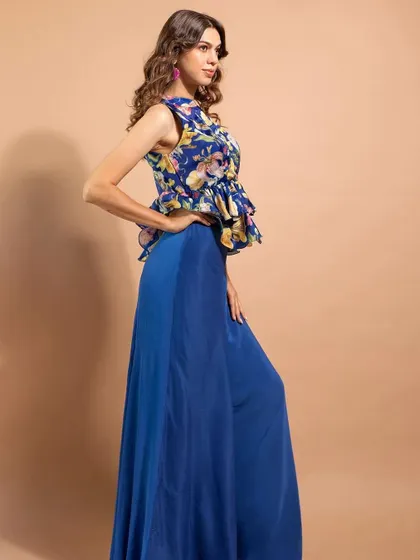 A full-length shot from the campaign, featuring a floral peplum top and royal blue pants. The makeup is fresh and minimal, perfect for a daytime event.