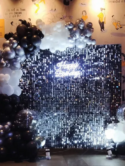For a chic and modern birthday, I created this dazzling silver sequin wall backdrop. Paired with a balloon arch in a sophisticated black, silver, and white palette and a "Happy Birthday" neon sign, this setup is perfect for a glamorous celebration.