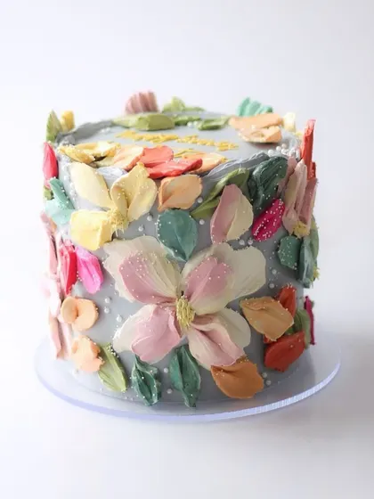 A beautiful cake featuring a palette knife painting technique with buttercream. The colorful, textured flowers create a stunning, impressionistic garden effect.