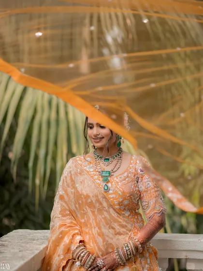 An artistic portrait of the bride with her orange dupatta gently flowing in the wind.