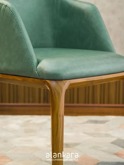 A detail shot of the 'Green Arber' chair, focusing on the seamless connection between the upholstered seat and the expertly crafted teak wood legs.
