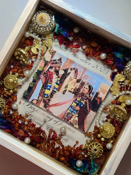 This piece captures the grandeur of a traditional wedding. I preserved the couple's varmala, complete with intricate golden kaleera pieces and pearls, around their photo in a beautiful white wooden frame.