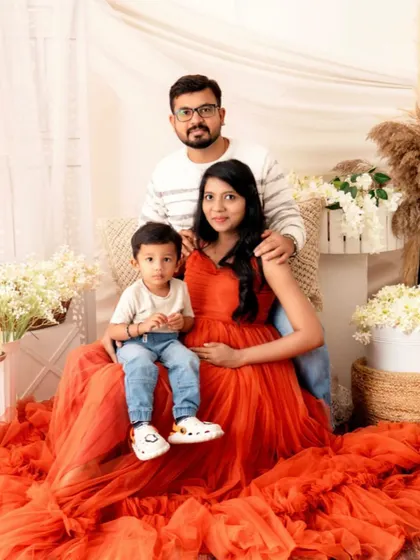 A bright and happy family maternity portrait. The vibrant orange gown and the relaxed poses capture the joyful and loving spirit of this family.