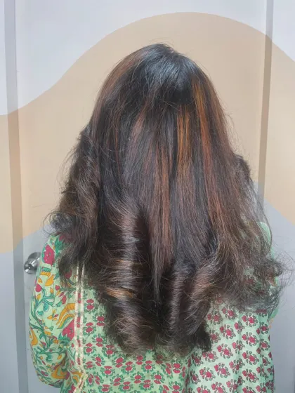 A back view of a client's hair after a highlight and styling session, showing off the beautiful blend of colors and bouncy curls.
