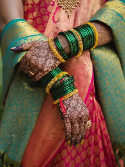 A detail shot focusing on the bride's hands, adorned with green glass bangles and detailed henna. These elements are a significant part of the Maharashtrian bridal tradition.