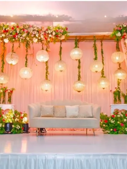 We create elegant and dreamy atmospheres for any occasion. This reception stage design uses soft drapery, lush floral arrangements, and beautiful hanging spherical lamps to produce a warm, inviting, and sophisticated ambiance.