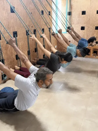 A closer look at students exploring different supported poses on the rope wall. This practice is beneficial for all levels, helping to build awareness and decompress the spine.