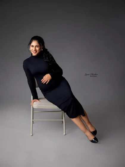 A chic and modern maternity portrait. The simple black dress, classic chair, and grey backdrop create a sophisticated and minimalist look that is effortlessly stylish.