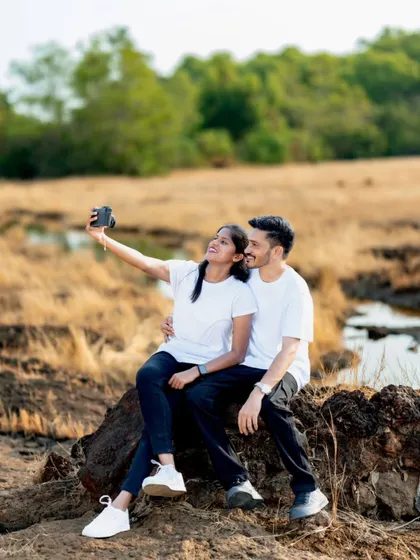A modern pre-wedding moment, with the couple taking a selfie with a vintage camera, blending old and new in a fun, candid shot.