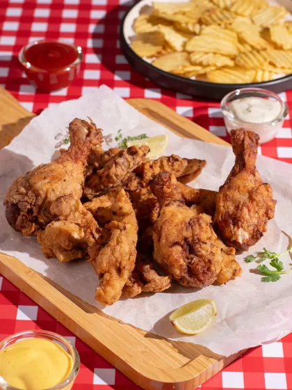 A classic platter of crispy fried chicken. We styled this shot with a picnic-style checkered cloth and various dips to create a fun, casual vibe that makes you crave a crunchy bite.