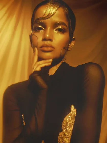A powerful and direct gaze, with the gold makeup and short, styled hair creating a strong, androgynous, high-fashion look.