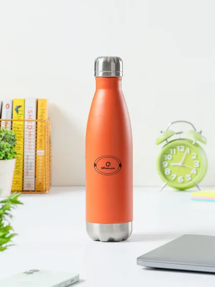 A lifestyle shot of a water bottle on a work desk. This simple, clean styling places the product in its intended environment, making it an aspirational accessory for any workspace.