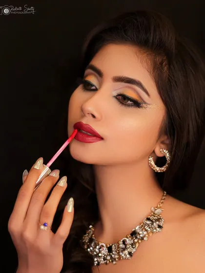 A creative shot showing the model applying lipstick. This adds a behind-the-scenes feel to the glamorous portrait.