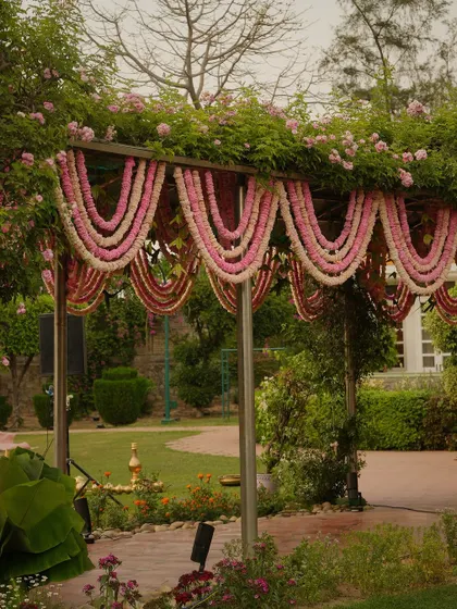 The entrance arch was draped with beautiful garlands of pink and white flowers, creating a soft and welcoming gateway into the garden wedding.