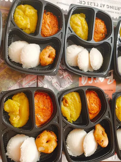Breakfast boxes packed and ready for an event. Each box contains idli, medhu vada, kesari, and chutney, making it a convenient and complete meal for guests.