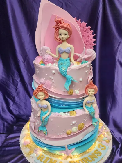 Under the sea! This two-tier mermaid cake is a magical creation, with Ariel and her friends swimming around a beautiful underwater castle. The light-up feature adds an extra touch of enchantment.