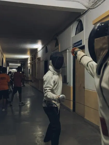 A view from behind a fencer, showing their perspective as they face an opponent down the long corridor we use for training.