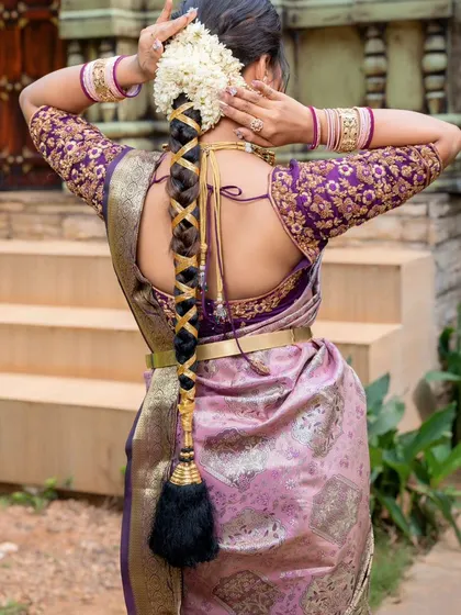 A back view highlighting the traditional braided hairstyle and the beautiful blouse design of the lavender and pink silk saree.