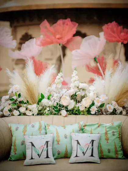 The seating area for the bride, adorned with personalized cushions and surrounded by whimsical floral arrangements. Personalization is key to making a wedding feel unique.