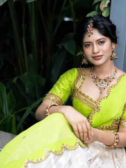 A sitting portrait of the model, giving a clearer view of the intricate choker and maang tikka from our silver collection.