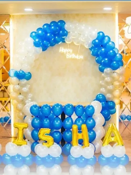 A balloon arch and name decoration in blue, white, and gold. This setup is perfect for a boy's birthday party, creating a festive and personalized photo backdrop.
