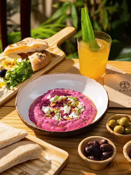 A vibrant beetroot hummus at Kaia Goa. The bright pink dip and fresh pita are shot in natural sunlight to emphasize the healthy, fresh ingredients.