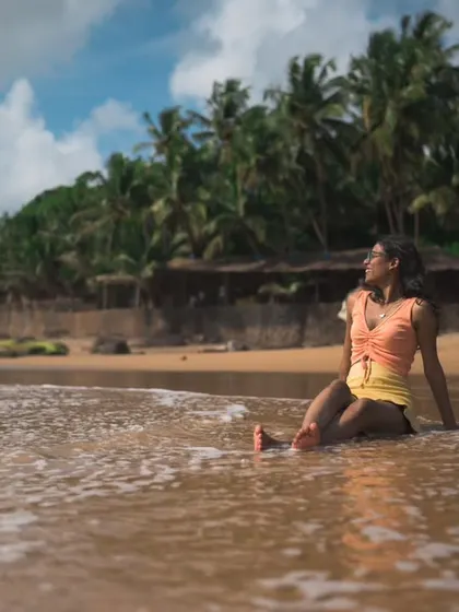 A candid shot from the same beach session in Goa. This photo captures a moment of peaceful reflection against the backdrop of palm trees and the open sea.