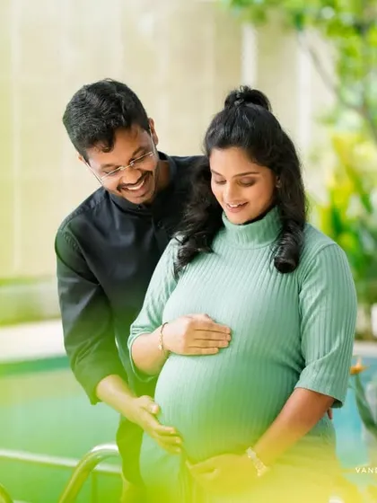 A bright and airy shot of a couple enjoying a moment together near a pool, surrounded by plants. This highlights a fresh and modern style for an outdoor pregnancy photoshoot.