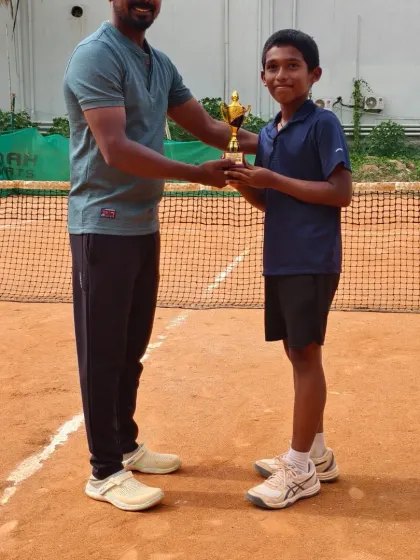Presenting the winner's trophy to Lawan, our Under 14 champion. My greatest satisfaction comes from personally congratulating players on their tournament achievements.