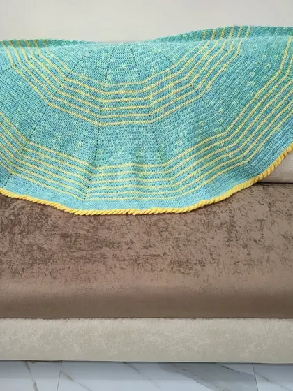 The lime green and yellow semi-circle shawl spread across a sofa. The yarn has a lovely heathered quality, giving the green a soft, multi-tonal look.