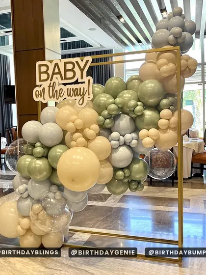 A chic and modern "Baby on the way!" baby shower. The minimalist gold frame is adorned with a sophisticated balloon arrangement in sage green, cream, and grey.