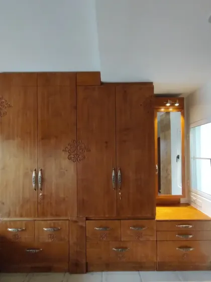 Another angle of the Sampada Home wardrobe, showing its stepped design that adapts to the room's architecture while providing a mix of drawers, cabinets, and a dressing mirror.