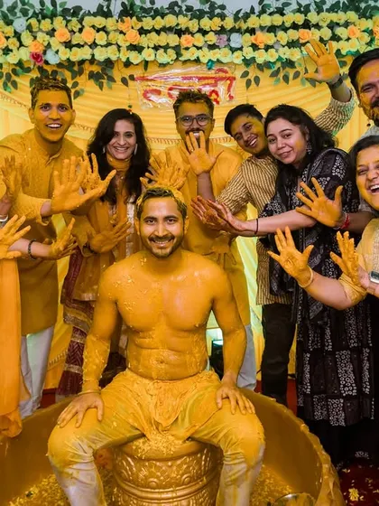 The whole gang. The groom poses with his friends and family, all showing off their turmeric-covered hands, a perfect group photo memory.