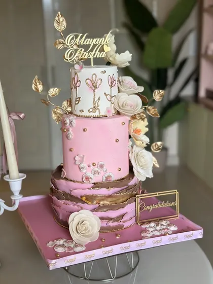 From behind the scenes to the final look, this three-tiered cake in pink and gold is a labor of love. It features a textured bottom tier, hand-painted floral details, and delicate sugar flowers.