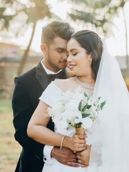 A romantic embrace in the golden hour light. The bride's off-the-shoulder gown and glowing makeup look absolutely perfect.